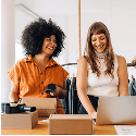 A photo of two women, one working on a laptop and the other scanning products.